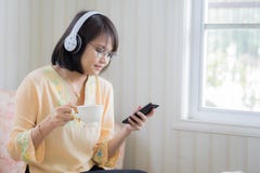 Piękna kobieta relaksuje dalej z hełmofonami i smartphone zdjęcia stock Piękna kobieta relaksuje dalej z hełmofonami i smartphone zdjęcia stock