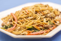 Piatto bianco con Yakisoba su fondo blu fotografia stock libera da diritti Piatto bianco con Yakisoba su fondo blu fotografia stock libera da diritti