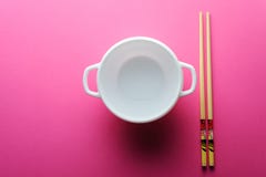 Piatto bianco dei bastoni cinesi su un fondo rosa fotografia stock libera da diritti Piatto bianco dei bastoni cinesi su un fondo rosa fotografia stock libera da diritti