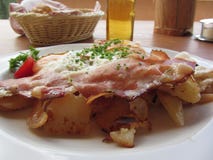 Piatto tirolese del sud tipico con la macchietta, le uova fritte, le patate e la erba cipollina fotografie stock libere da diritti Piatto tirolese del sud tipico con la macchietta, le uova fritte, le patate e la erba cipollina fotografie stock libere da diritti