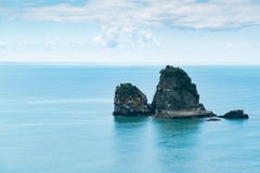 Piccola isola della roccia sull'orizzonte del litorale fotografia stock Piccola isola della roccia sull'orizzonte del litorale fotografia stock