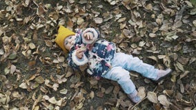 Piccola ragazza sveglia che si siede in un mucchio delle foglie gialle stock footage Piccola ragazza sveglia che si siede in un mucchio delle foglie gialle stock footage