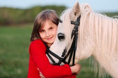 Piccola ragazza in un vestito rosso che abbraccia il suo testa un cavallo bianco fotografia stock libera da diritti Piccola ragazza in un vestito rosso che abbraccia il suo testa un cavallo bianco fotografia stock libera da diritti