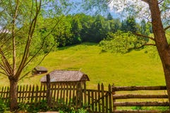 Piccole capanne rurali in mezzo ai prati verdi nelle montagne fotografia stock Piccole capanne rurali in mezzo ai prati verdi nelle montagne fotografia stock