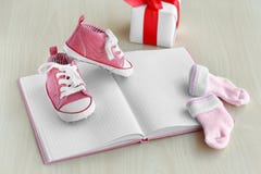 Piccole scarpe di bambino, taccuino, calzini e scatola attuale su fondo di legno immagini stock libere da diritti Piccole scarpe di bambino, taccuino, calzini e scatola attuale su fondo di legno immagini stock libere da diritti