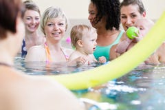 Piccoli bambini e loro le madri che giocano con le palle al corso di nuoto del bambino immagini stock Piccoli bambini e loro le madri che giocano con le palle al corso di nuoto del bambino immagini stock