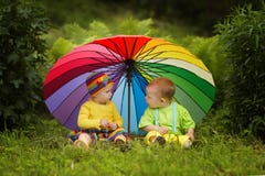 Piccoli bambini sotto l'ombrello variopinto immagini stock Piccoli bambini sotto l'ombrello variopinto immagini stock