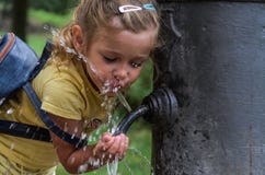 Piccolo bambino adorabile della ragazza beve l'acqua dalla fontanella “naso romano “ immagini stock libere da diritti Piccolo bambino adorabile della ragazza beve l'acqua dalla fontanella “naso romano “ immagini stock libere da diritti