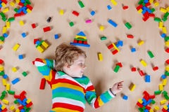 Piccolo bambino biondo che gioca con i blocchi di legno variopinti dell'interno Immagine Stock Piccolo bambino biondo che gioca con i blocchi di legno variopinti dell'interno Immagine Stock