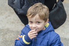 Piccolo bambino che mangia popcorn in un parco immagini stock Piccolo bambino che mangia popcorn in un parco immagini stock