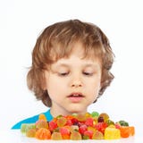 Piccolo bambino con le caramelle colorate della gelatina su fondo bianco fotografia stock libera da diritti Piccolo bambino con le caramelle colorate della gelatina su fondo bianco fotografia stock libera da diritti