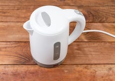 Piccolo bollitore elettrico di plastica bianco su una vecchia tavola di legno immagini stock libere da diritti Piccolo bollitore elettrico di plastica bianco su una vecchia tavola di legno immagini stock libere da diritti