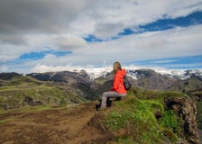 Piccolo zaino della giovane donna attiva della viandante che si siede godendo del paesaggio del vulcano con la valle verde delle fotografia stock libera da diritti Piccolo zaino della giovane donna attiva della viandante che si siede godendo del paesaggio del vulcano con la valle verde delle fotografia stock libera da diritti