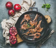 Piec na grillu jagnięcy mięso kotleciki słuzyć z świeżymi granatowami, popielaty tło obraz stock Piec na grillu jagnięcy mięso kotleciki słuzyć z świeżymi granatowami, popielaty tło obraz stock