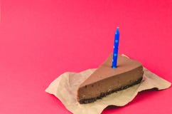 A piece of Chocolate cheesecake with blue candle on a red background stock images A piece of Chocolate cheesecake with blue candle on a red background stock images