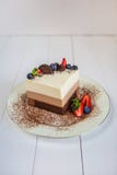 A piece of a mousse cake three chocolate stands on a plate, sprinkled with grated chocolate, and decorated with berries stock photo A piece of a mousse cake three chocolate stands on a plate, sprinkled with grated chocolate, and decorated with berries stock photo