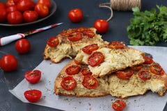 Pieces of focaccia with cherry tomatoes are located on parchment on a dark background. stock images Pieces of focaccia with cherry tomatoes are located on parchment on a dark background. stock images