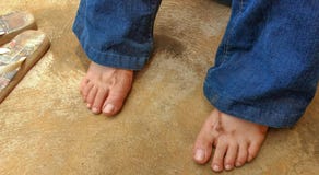 Pieds sales du ` s de fille se reposant avec des bascules à côté de elle après travail dans le jardin images stock Pieds sales du ` s de fille se reposant avec des bascules à côté de elle après travail dans le jardin images stock