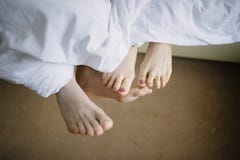 Pies del hombre y de la mujer en primer de la cama imagenes de archivo Pies del hombre y de la mujer en primer de la cama imagenes de archivo
