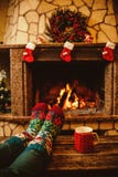 Pies en calcetines de lana por la chimenea de la Navidad La mujer se relaja imágenes de archivo libres de regalías Pies en calcetines de lana por la chimenea de la Navidad La mujer se relaja imágenes de archivo libres de regalías