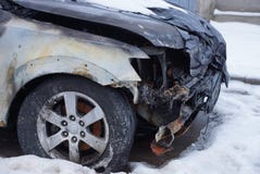 Pieza de un coche negro quemado en un desplome con un tope y una rueda en la nieve en la calle fotografía de archivo libre de regalías Pieza de un coche negro quemado en un desplome con un tope y una rueda en la nieve en la calle fotografía de archivo libre de regalías