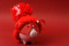 Piggy Bank In Love With Red Heart Sunglasses With Red Hat And Pom-pom Standing On Red Background Royalty Free Stock Photos Piggy Bank In Love With Red Heart Sunglasses With Red Hat And Pom-pom Standing On Red Background Royalty Free Stock Photos
