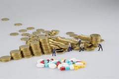 Pila de moneda de oro con la gente y la medicina miniatura imagen de archivo libre de regalías Pila de moneda de oro con la gente y la medicina miniatura imagen de archivo libre de regalías