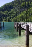 Pilastro di legno su un lago nelle alpi in primavera contro il contesto delle montagne fotografia stock libera da diritti Pilastro di legno su un lago nelle alpi in primavera contro il contesto delle montagne fotografia stock libera da diritti