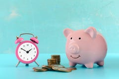 Piles et une pile des pièces de monnaie, d'un réveil rose et d'une tirelire sur un fond de turquoise Le symbole du photos libres de droits Piles et une pile des pièces de monnaie, d'un réveil rose et d'une tirelire sur un fond de turquoise Le symbole du photos libres de droits