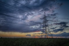 Pilón de la electricidad en la oscuridad y tormenta en el horizonte Foto de archivo Pilón de la electricidad en la oscuridad y tormenta en el horizonte Foto de archivo