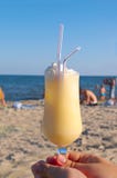 Pina-colada cocktail on the beach in woman hand