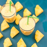 Pineapple smoothie with fresh pineapple on wooden blue table. stock images Pineapple smoothie with fresh pineapple on wooden blue table. stock images
