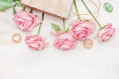 Pink pale roses paper shopping bag and round sign with message for you and heart on white wooden background, top view royalty free stock photo Pink pale roses paper shopping bag and round sign with message for you and heart on white wooden background, top view royalty free stock photo