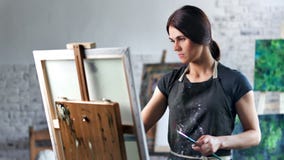 Pintor de sexo femenino hermoso concentrado feliz que goza dibujando la imagen en tiro medio del estudio del arte metrajes Pintor de sexo femenino hermoso concentrado feliz que goza dibujando la imagen en tiro medio del estudio del arte metrajes