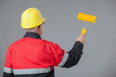 Pintor em um capacete amarelo que guarda um rolo amarelo Fotos de Stock Pintor em um capacete amarelo que guarda um rolo amarelo Fotos de Stock