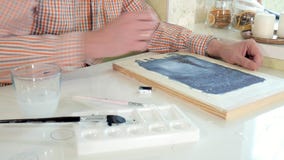 Pintura adulta del hombre con las pinturas coloreadas de la acuarela en un cierre casero del estudio para arriba Pintura adulta del hombre con las pinturas coloreadas de la acuarela en un cierre casero del estudio para arriba