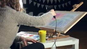 A pintura das mulheres adultas com pinturas coloridas da aquarela e seca com um secador de cabelo em uma escola de arte A pintura das mulheres adultas com pinturas coloridas da aquarela e seca com um secador de cabelo em uma escola de arte
