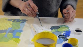 Pintura de las mujeres adultas con las pinturas acrílicas coloreadas en un cierre de la escuela de arte para arriba Pintura de las mujeres adultas con las pinturas acrílicas coloreadas en un cierre de la escuela de arte para arriba
