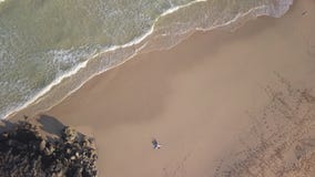 Pionowo widok z lotu ptaka dziewczyny lying on the beach w opustoszałej plaży zbiory Pionowo widok z lotu ptaka dziewczyny lying on the beach w opustoszałej plaży zbiory