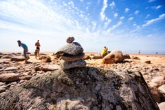 Piramide di vecchie pietre sulla spiaggia con i vacanzieri del sole Immagini Stock Piramide di vecchie pietre sulla spiaggia con i vacanzieri del sole Immagini Stock