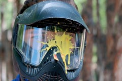 Pittura gialla della macchia su una maschera del vetro di protezione per il gioco del paintball fuori La testa di un giovane in u immagini stock libere da diritti Pittura gialla della macchia su una maschera del vetro di protezione per il gioco del paintball fuori La testa di un giovane in u immagini stock libere da diritti