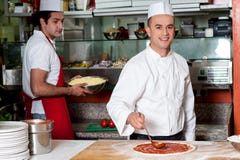 Pizza för kockbagaredanande på kök royaltyfri bild Pizza för kockbagaredanande på kök royaltyfri bild
