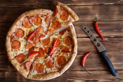 Pizza hecha en casa con mentiras de los salchichones y de las pimientas de chile rojo al lado de un cuchillo del queso en una sup imagen de archivo Pizza hecha en casa con mentiras de los salchichones y de las pimientas de chile rojo al lado de un cuchillo del queso en una sup imagen de archivo