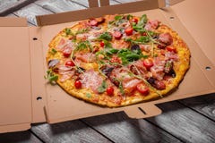 Pizza recentemente cozida Picante, meaty, pizza de queijo em uma caixa da caixa Pizza em um fundo cinzento Conceito da entrega da foto de stock Pizza recentemente cozida Picante, meaty, pizza de queijo em uma caixa da caixa Pizza em um fundo cinzento Conceito da entrega da foto de stock