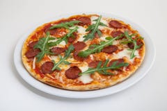 Pizza with salami, cheese and arugula