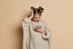 Piękni blond małych dziewczynek spojrzenia przy telefonem confusedly, pracowniana fotografia na tle zdjęcie royalty free Piękni blond małych dziewczynek spojrzenia przy telefonem confusedly, pracowniana fotografia na tle zdjęcie royalty free