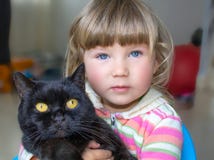 Piękna mała dziewczynka z niebieskimi oczami trzyma czarnego kota Przyjaźń z zwierzętami domowymi fotografia royalty free Piękna mała dziewczynka z niebieskimi oczami trzyma czarnego kota Przyjaźń z zwierzętami domowymi fotografia royalty free