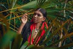 Piękna młoda modna kobieta z uzupełnia i eleganccy boho akcesoria pozuje na naturalnym tropikalnym tle obraz stock Piękna młoda modna kobieta z uzupełnia i eleganccy boho akcesoria pozuje na naturalnym tropikalnym tle obraz stock