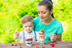 Piękna szczęśliwa matka i jej dziecko chłopiec łasowanie ablegrujący deser w zieleni uprawiamy ogródek w pogodnym letnim dniu zdjęcia stock Piękna szczęśliwa matka i jej dziecko chłopiec łasowanie ablegrujący deser w zieleni uprawiamy ogródek w pogodnym letnim dniu zdjęcia stock