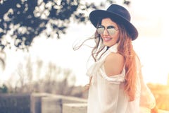 Piękna uśmiechnięta młoda kobieta outdoors z okularami przeciwsłonecznymi i kapeluszem, biała koszula fotografia royalty free Piękna uśmiechnięta młoda kobieta outdoors z okularami przeciwsłonecznymi i kapeluszem, biała koszula fotografia royalty free